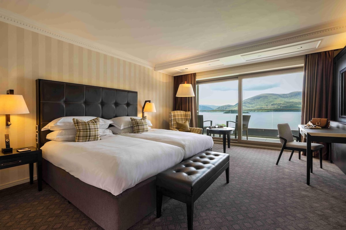 A hotel room with a large bed, a desk, and a view of a lake.
