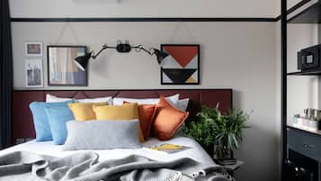 Une chambre à coucher moderne avec un lit soigneusement fait, une tête de lit ornée de motifs géométriques et une plante sur la table de chevet.