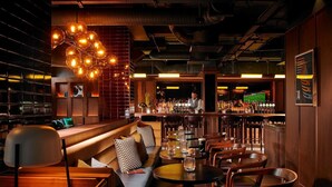 A bar area with wooden furniture, a bartender, and a well-stocked bar counter. - The Mont (Dublin)