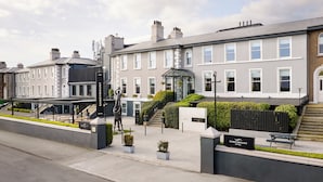 A hotel with a modern facade, a covered outdoor seating area, and a staircase leading to the entrance. - The Sandymount Hotel (Dublin)
