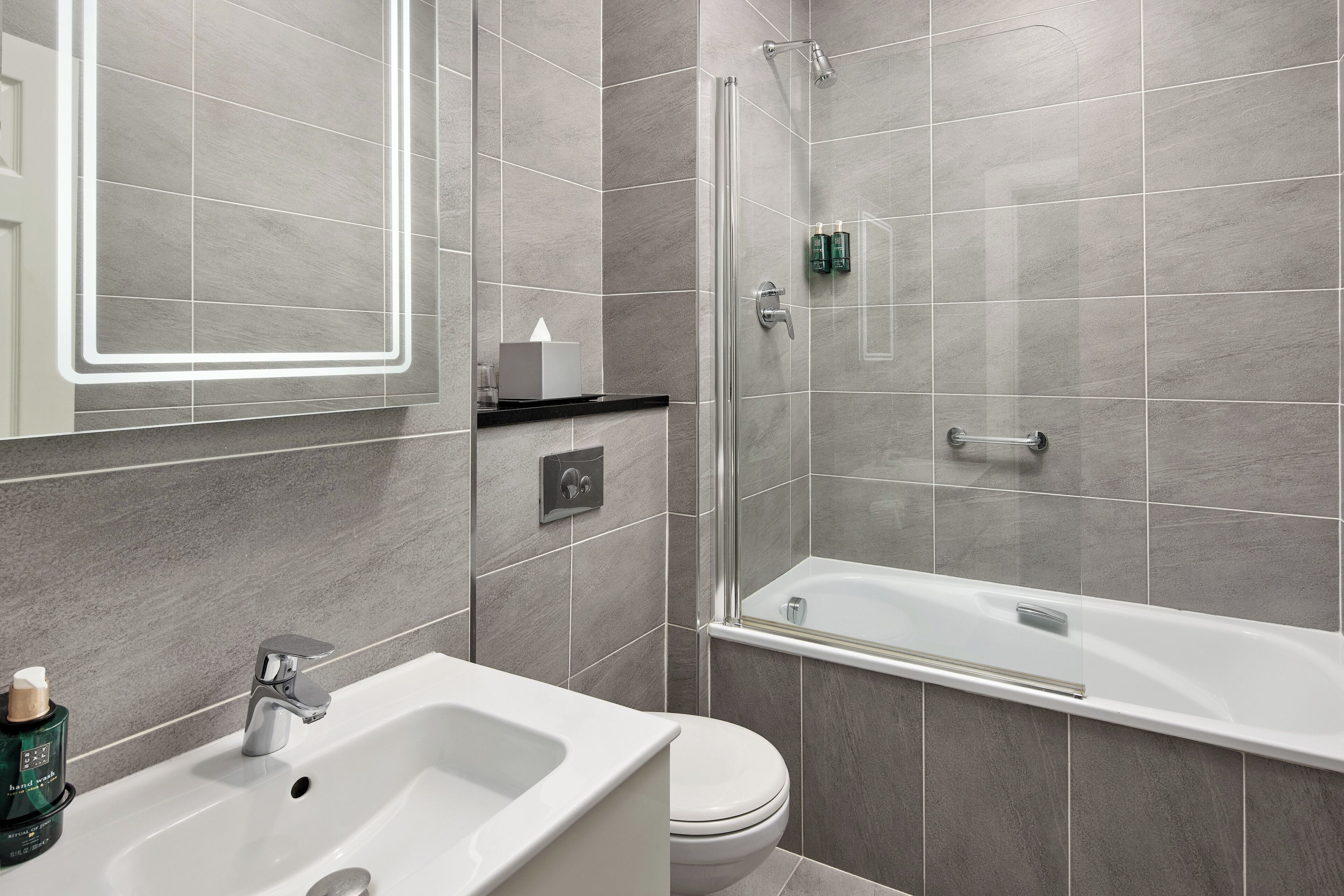 Een moderne badkamer met een wit wastafelmeubel, toilet en bad.