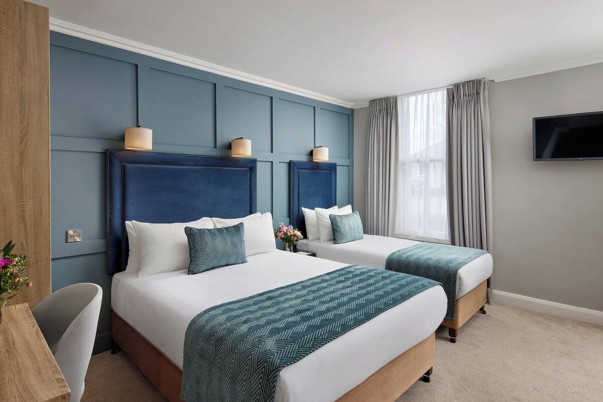 A hotel room with two beds, a TV, and a desk.