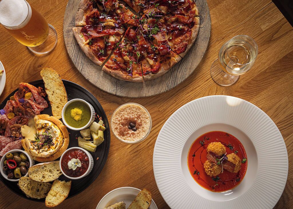 A variety of food items including pizza, bread, and dips on a wooden table.