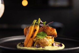 Un plat composé de poulet grillé, de carottes et d’une sauce verte, le tout servi dans une assiette.