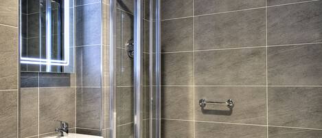 A modern bathroom with a glass-enclosed shower, a white sink, and a bathtub.
