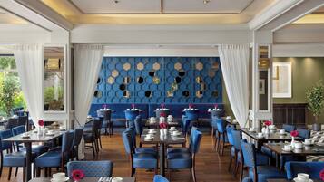 A restaurant with blue upholstered chairs, white table settings, and a blue patterned wall.