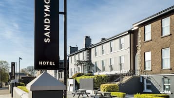 A hotel sign with the name "SANDYMOUNT HOTEL" and a paved walkway with picnic tables.