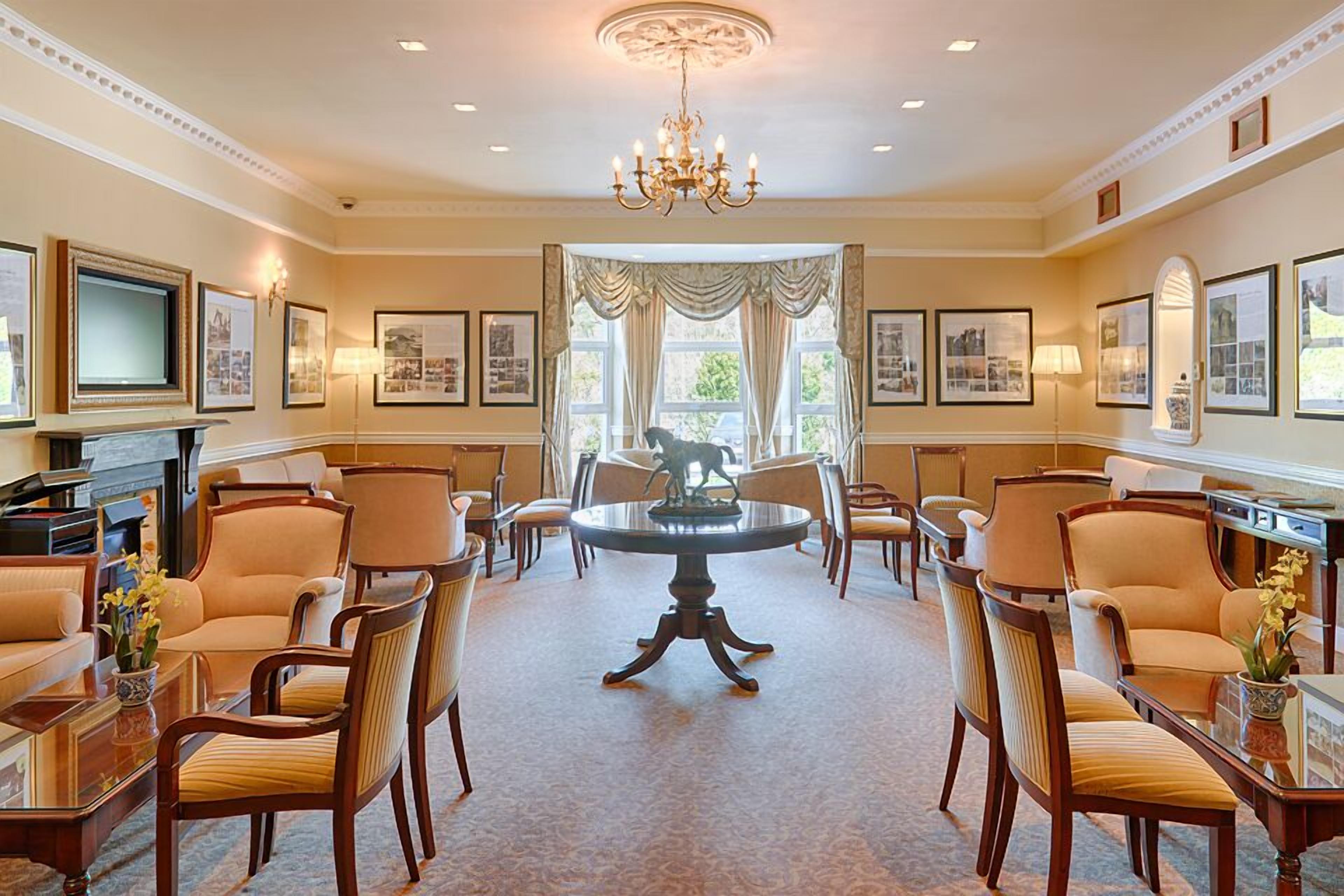A formal dining room with a chandelier, framed pictures, and a fireplace.