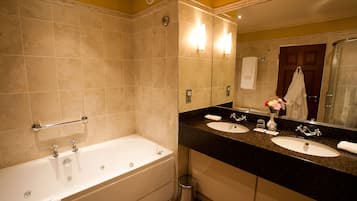 Un baño con bañera, dos lavamanos, tocador y un espejo grande.