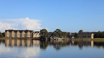 Un hotel al costat del llac amb diversos edificis, una torre destacada i una calma massa d'aigua que reflecteix les estructures.