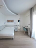Una habitación de hotel moderna con cama, escritorio y televisor.