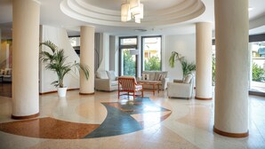A spacious lobby with large columns, a central seating area, and large windows allowing natural light. - Hotel Carlo Felice (Sassari)