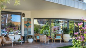 A modern hotel exterior with outdoor seating, large windows, and a garden area. - Hotel Carlo Felice (Sassari)
