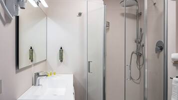 A modern bathroom with a glass-enclosed shower, a white sink, and a large mirror.