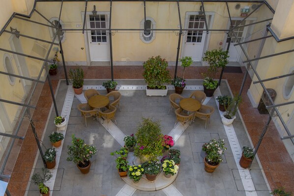A courtyard with outdoor seating, potted plants, and a central fountain. - Hotel Carlton on the Grand Canal (Venice)