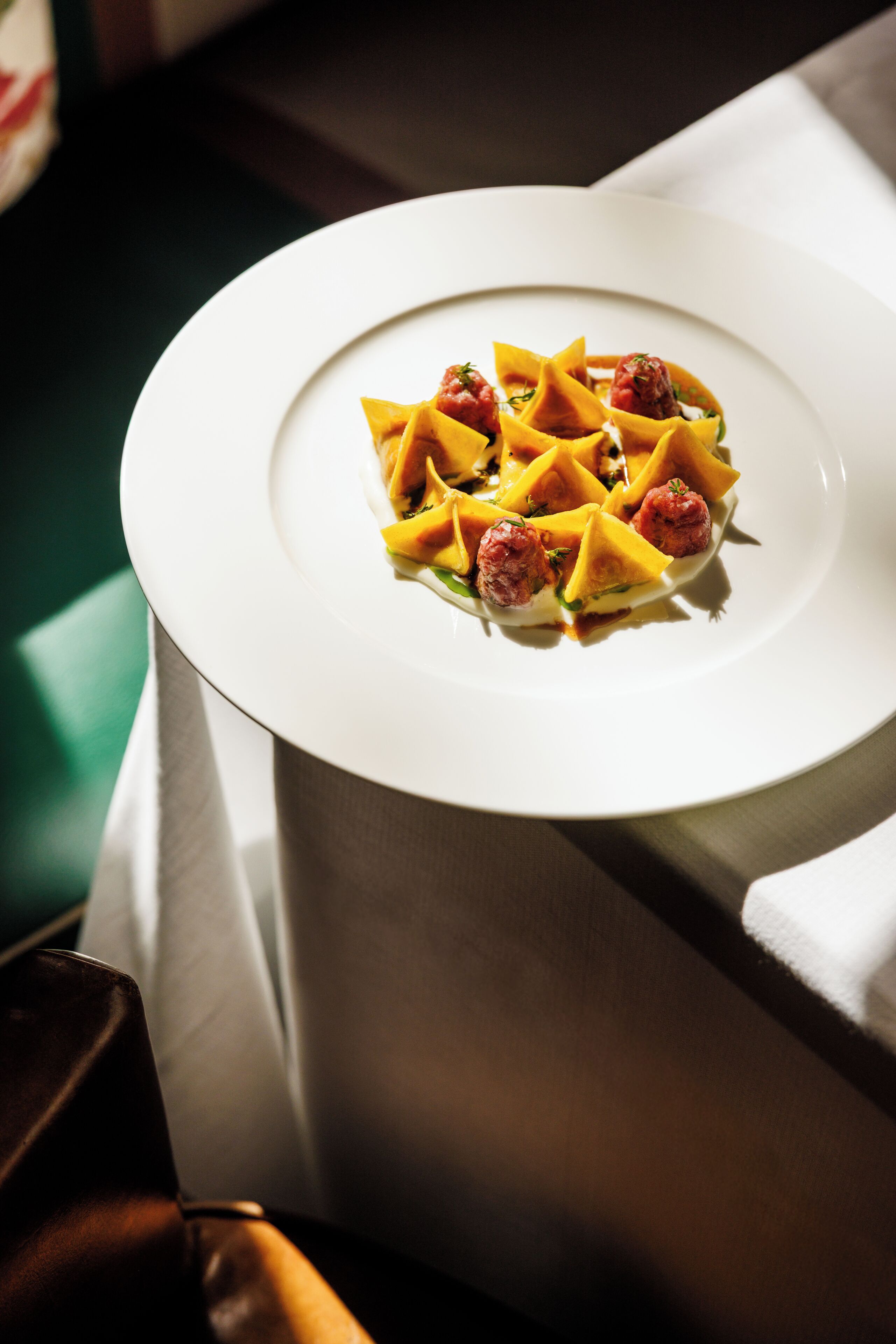 A white plate with a dish of food, a chair, and a table.