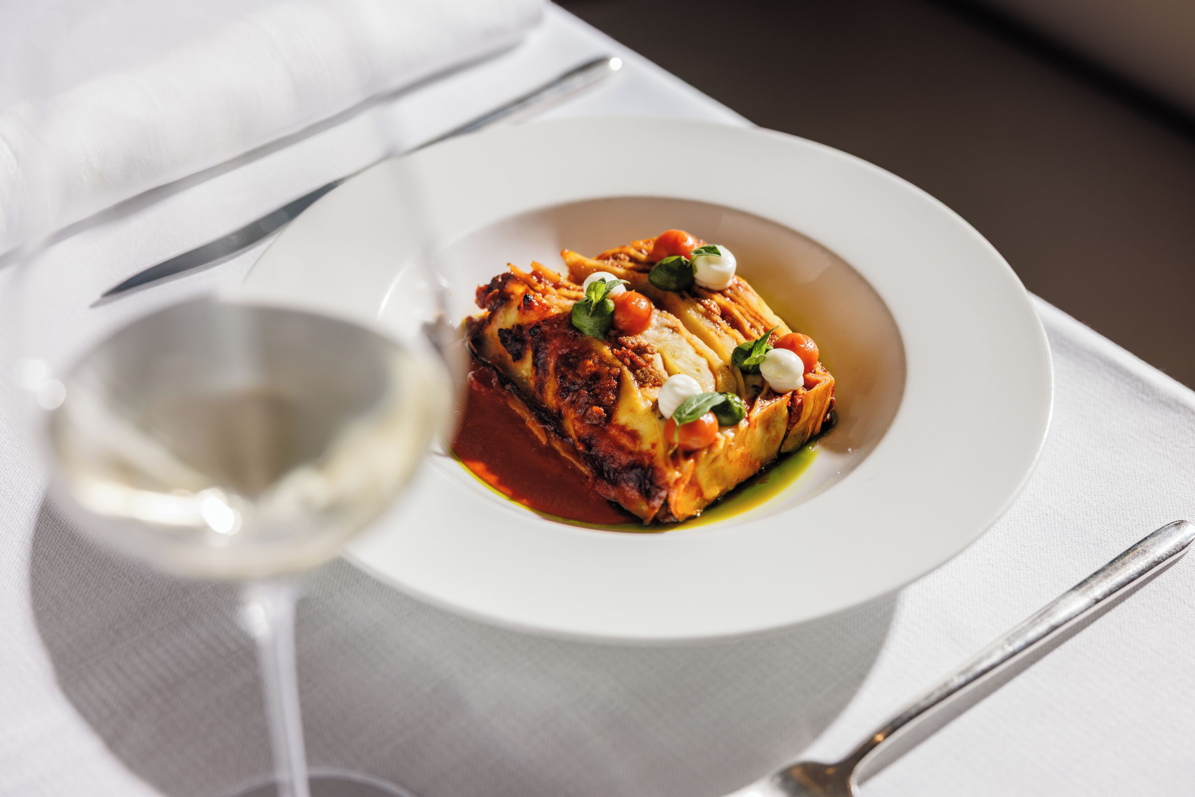 Un plato de comida con una copa de vino blanco sobre una mesa.