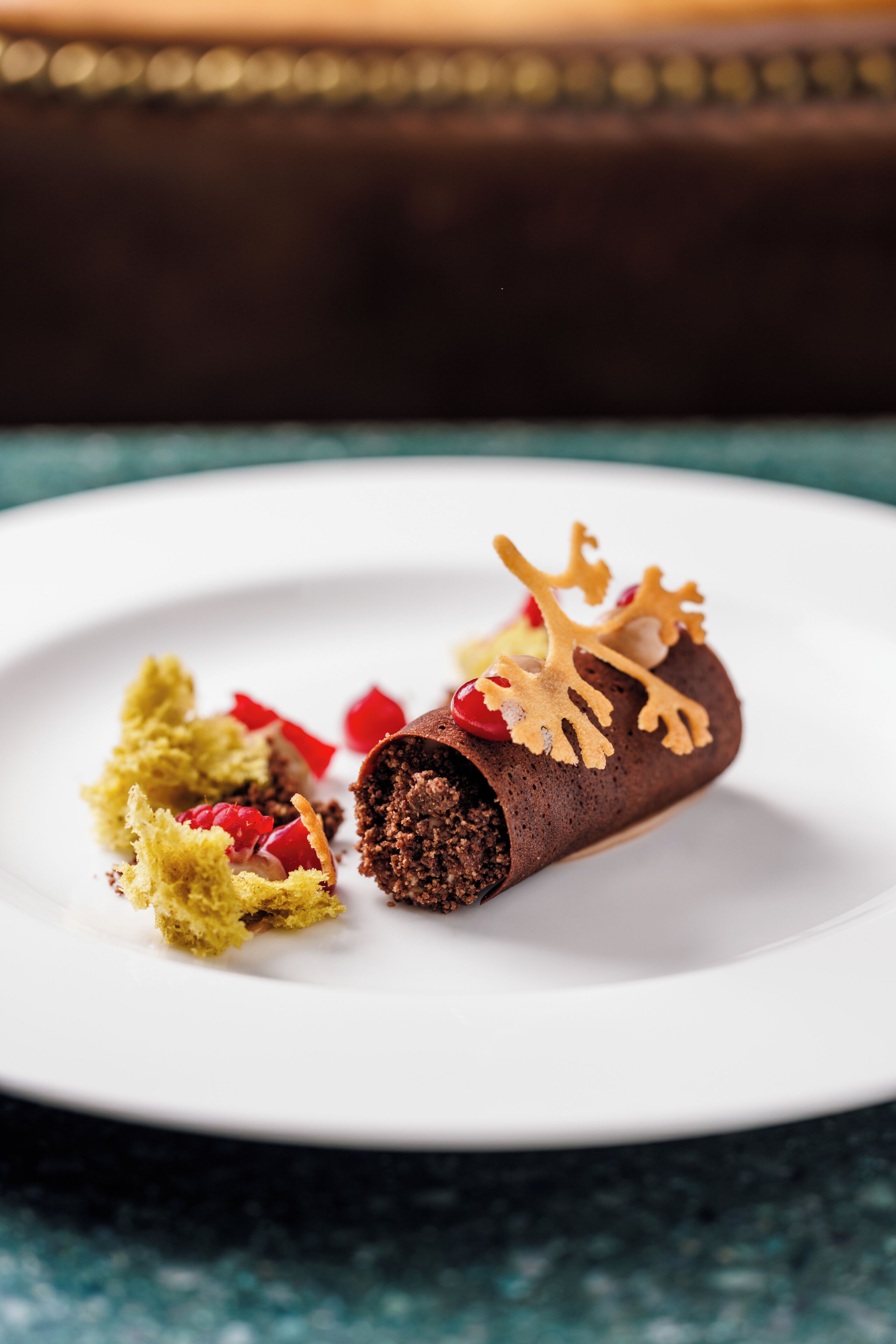 A chocolate dessert on a white plate with decorative elements.