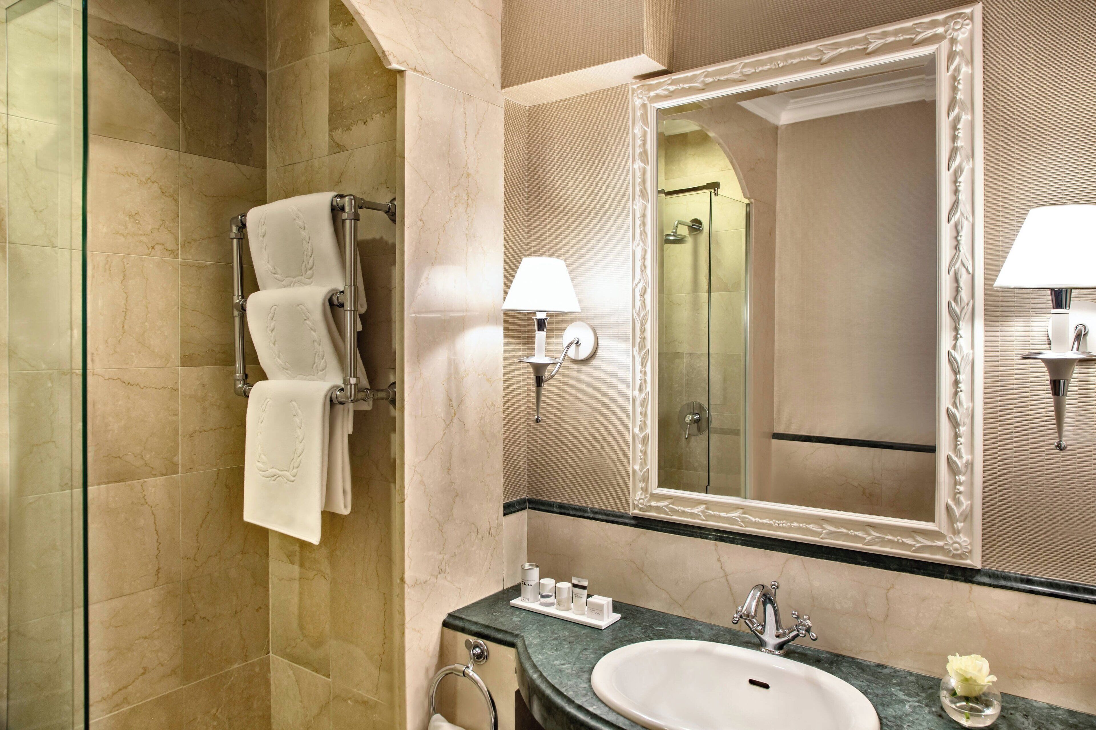 A bathroom with a marble floor, a sink, a mirror, and a towel rack.
