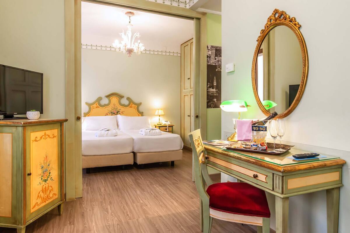 Une chambre d’hôtel comprenant un lit, un bureau avec un miroir, une télévision et un placard.