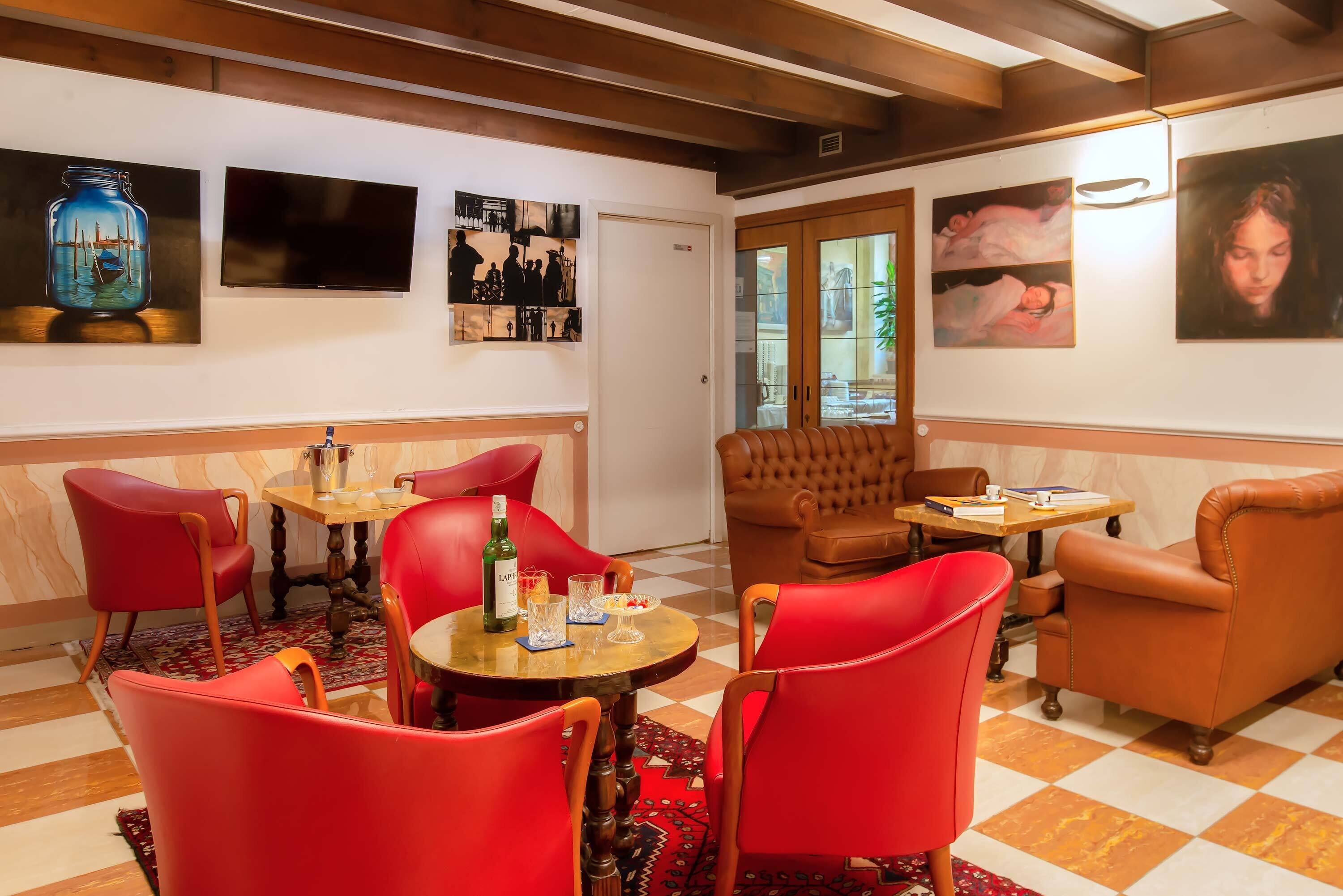A cozy room with red chairs, a wooden table, and artwork on the walls.