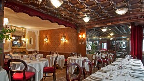 Een restaurant met meerdere eettafels, een patroon vloer en een versierd plafond.