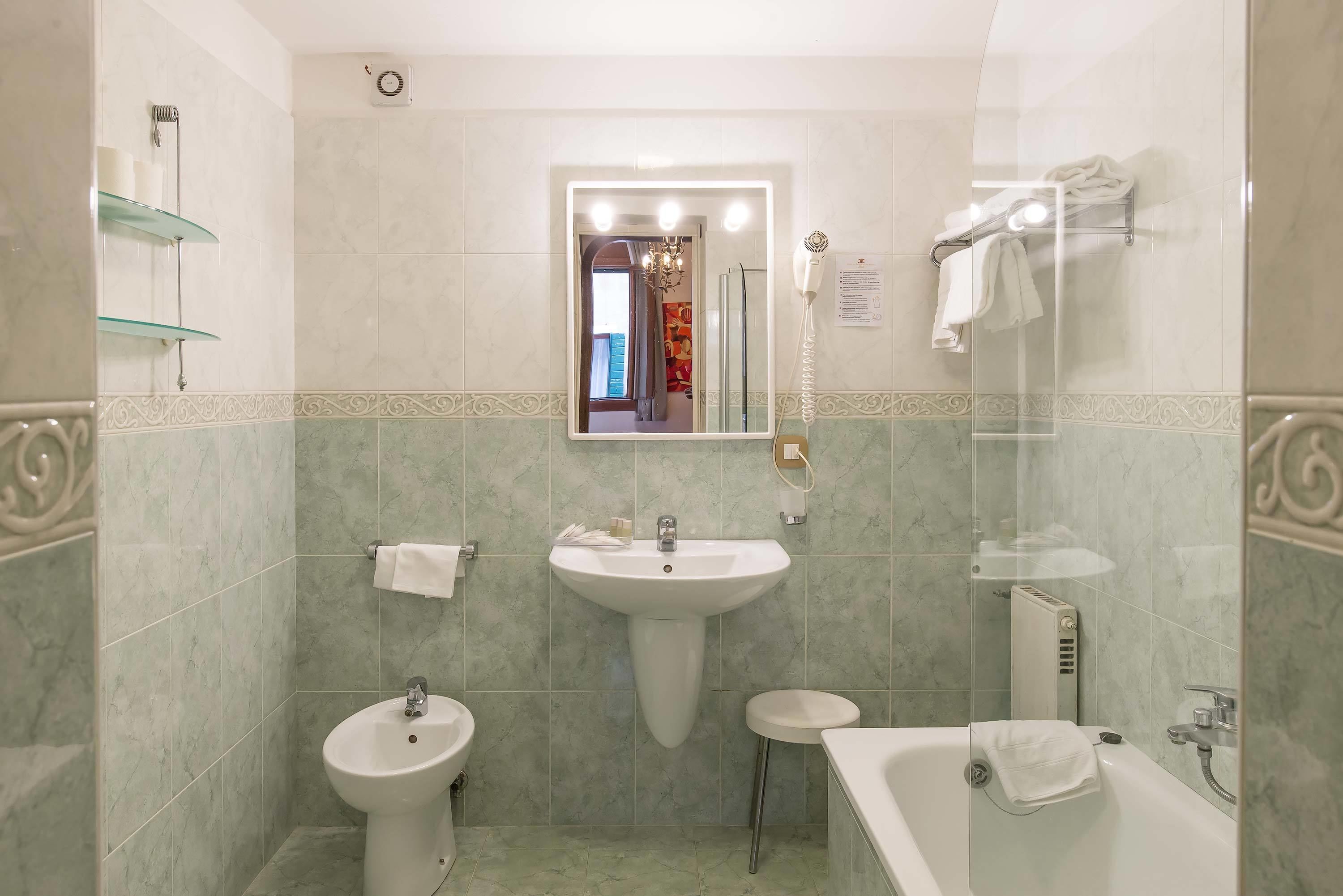 Une salle de bain comprenant un lavabo sur colonne, un meuble-lavabo, une baignoire et une douche à l’italienne.