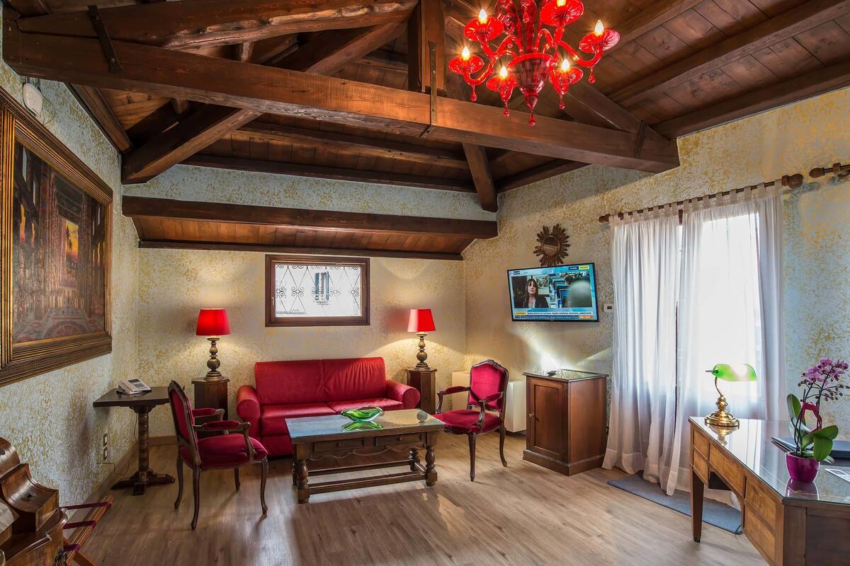 Un salon chaleureux avec un plafond en bois, un canapé rouge, une table basse en bois et deux lampes.