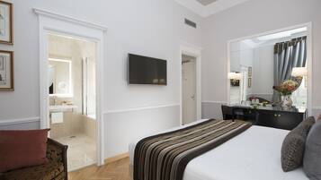 A hotel room with a large bed, a flat-screen TV, a desk with a mirror, and a bathroom visible through an open door.