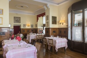 A dining area with tables set for service, wooden paneling on the walls, and framed artwork on the walls.