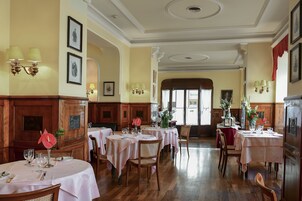 A dining area with multiple tables set for guests, wooden paneling on the walls, and framed artwork on the walls.