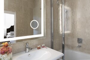 A bathroom with a white sink, a mirror, and a glass shower enclosure.