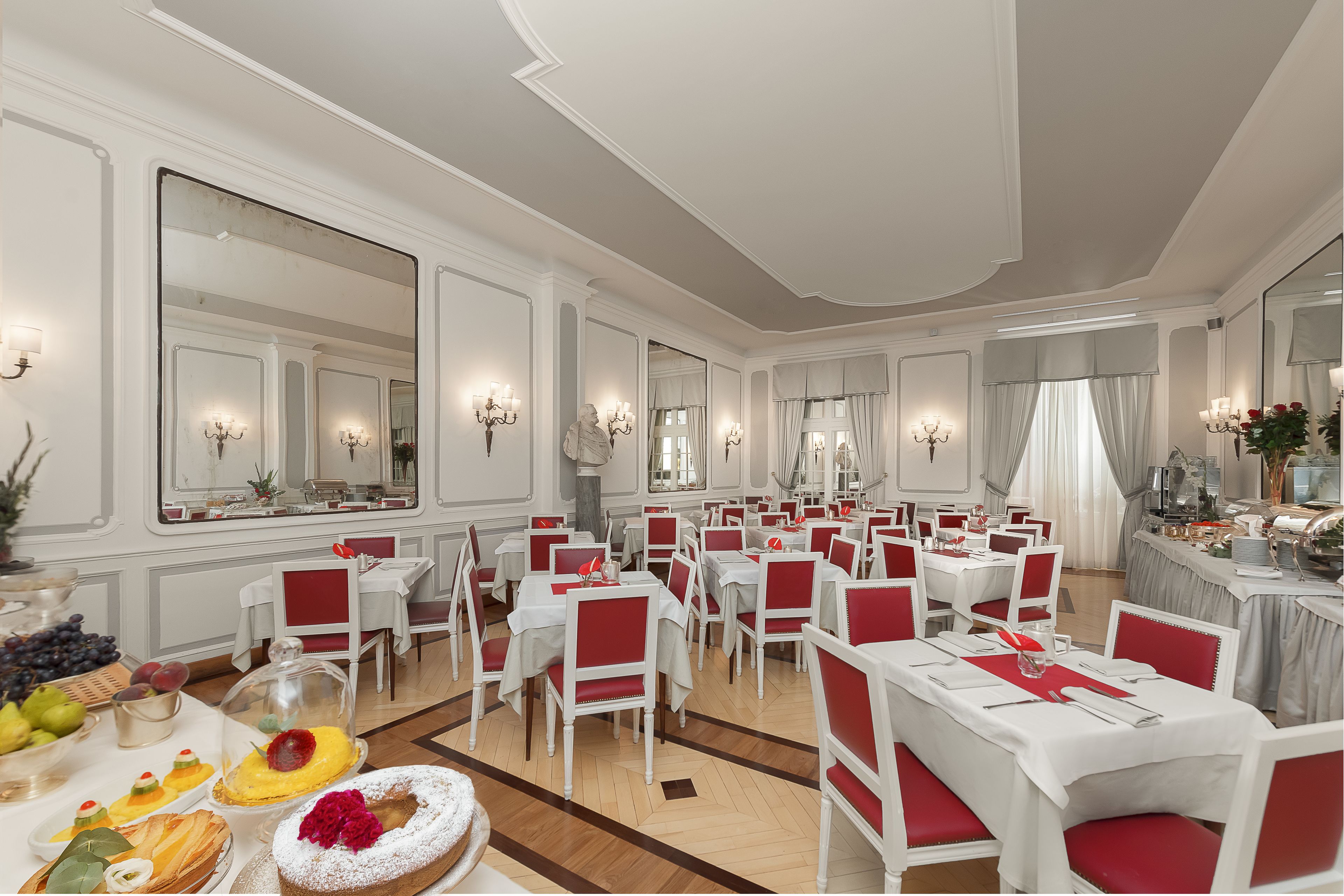 Une salle à manger élégante, dotée de plusieurs tables et chaises, de grands miroirs et de lustres.