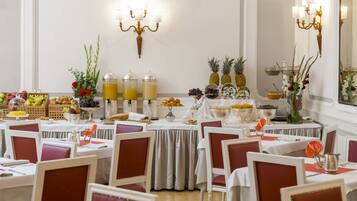 A dining area with tables set for guests, featuring a variety of fruits and beverages.