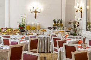 A dining area with tables set for guests, featuring a variety of fruits and beverages.
