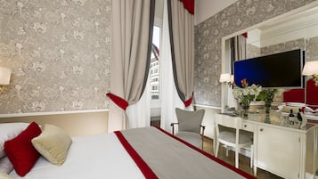 Una camera d'albergo con un letto, una scrivania, una sedia, una TV e uno specchio.