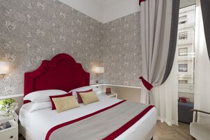 Ein Hotelzimmer mit einem großen Bett, einem roten Kopfteil und Blick auf ein Gebäude durch das Fenster.