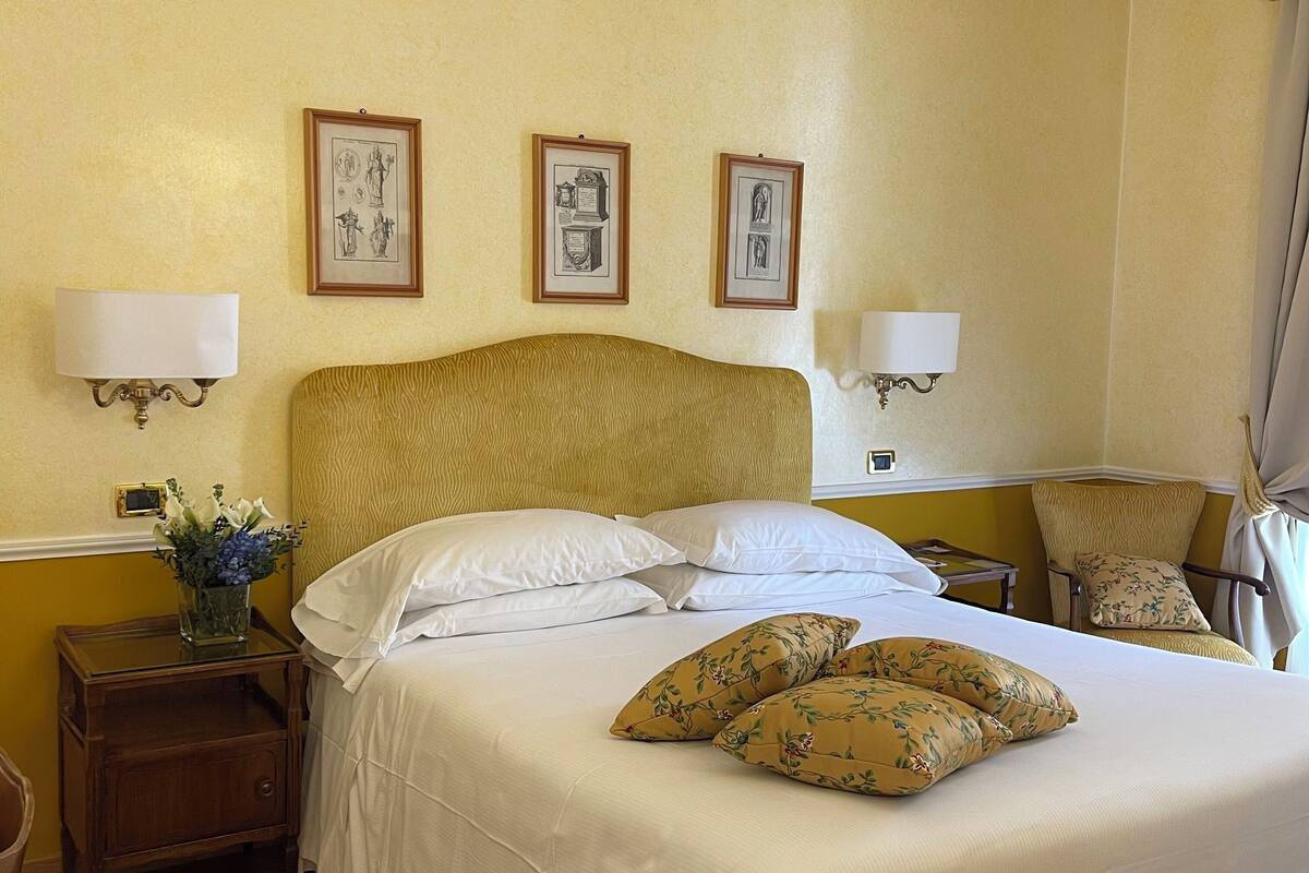 Ein Hotelzimmer mit einem großen Bett, zwei Wandlampen und drei gerahmten Bildern an der Wand.