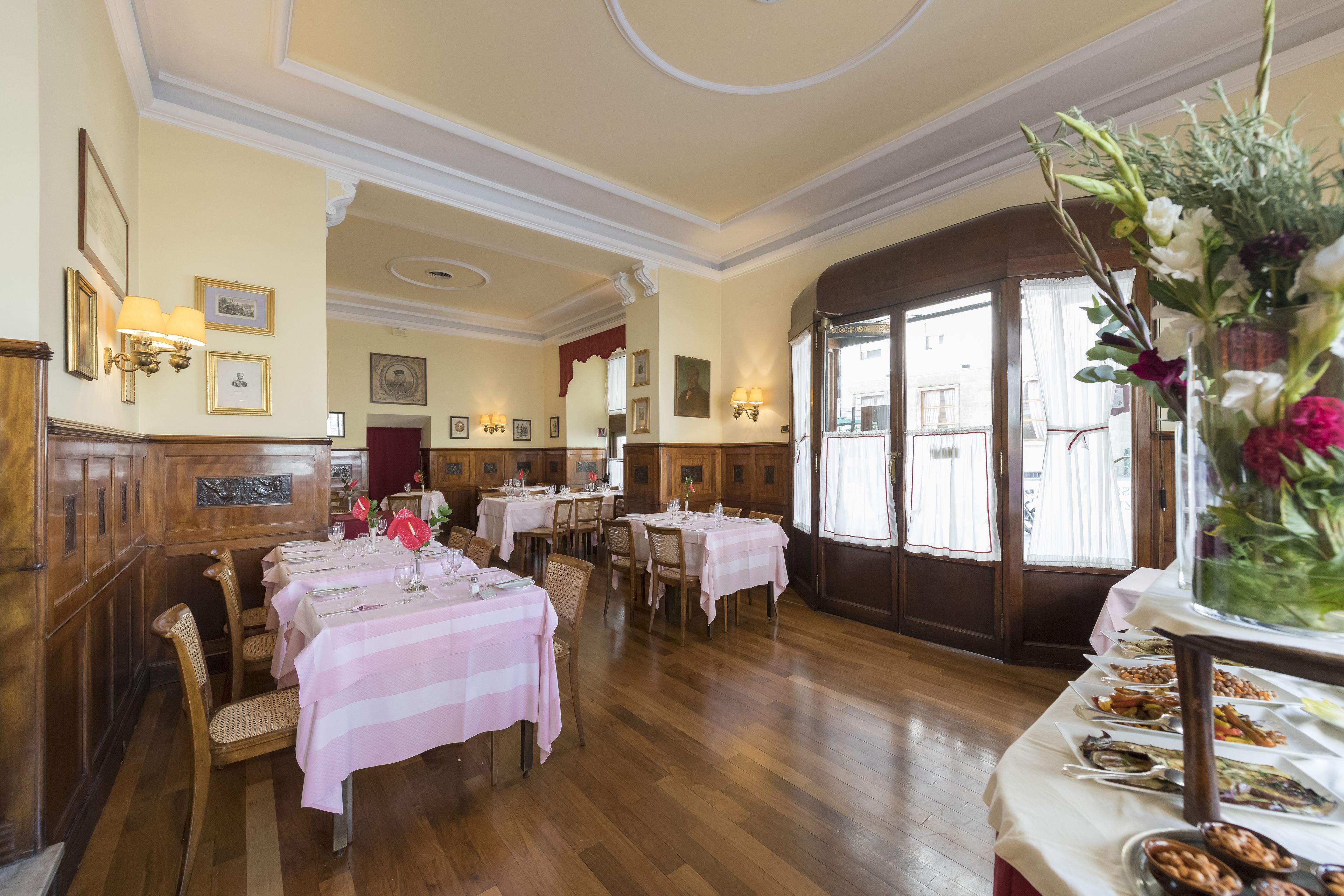 A dining area with wooden paneling, striped tablecloths, and a buffet with various dishes.