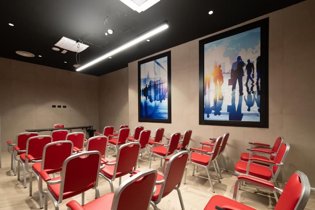 A conference room with red chairs and tables, a projector, and two large abstract paintings on the walls.
