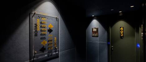 A hotel corridor with directional signs for rooms 401-410 and a door labeled 402.
