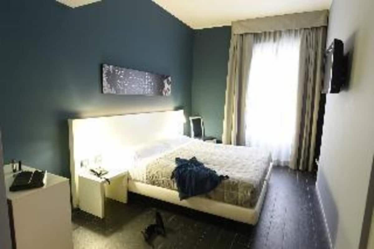 Een slaapkamer met een bed, nachtkastje en een raam met gordijnen.