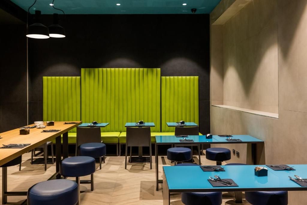 Un salón de conferencias moderno con una pared de acento verde, varias mesas y asientos azules.