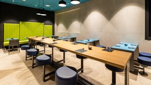 A modern conference room with long tables, blue chairs, and a green accent wall. - Smart Hotel Milano (Milan)
