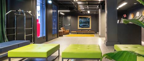 A modern lobby with green seating, a reception desk, and a large framed artwork on the wall.