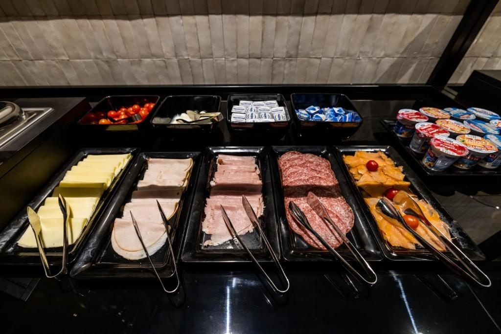 Un bufé con diversas opciones de comida, incluyendo carnes, quesos y frutas.