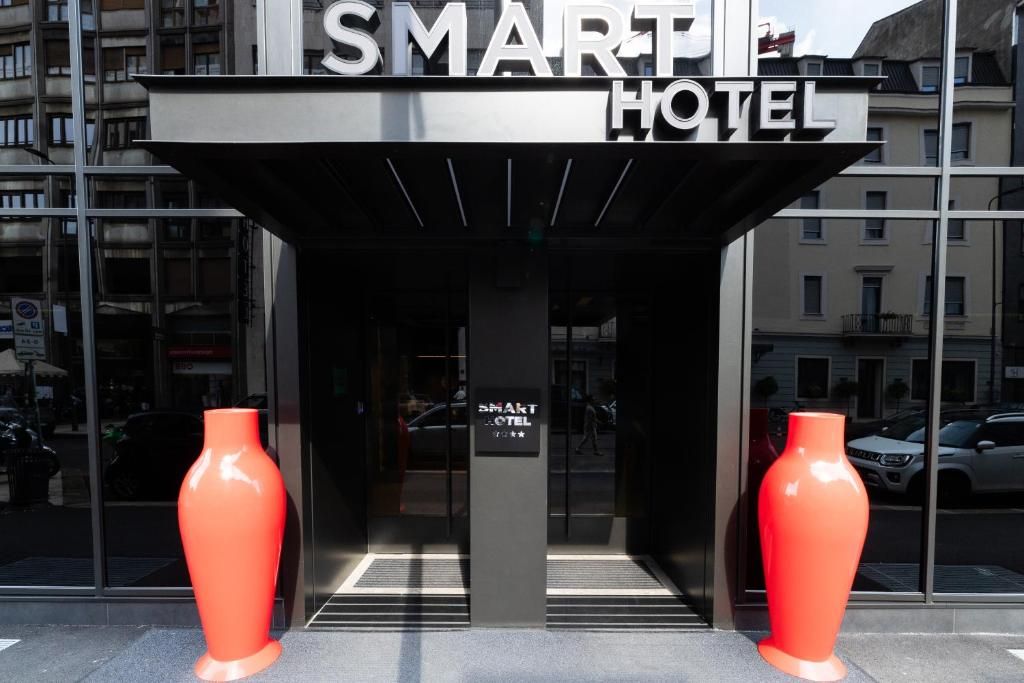The entrance to the SMART HOTEL with a modern design, featuring two large vases on either side of the entrance.
