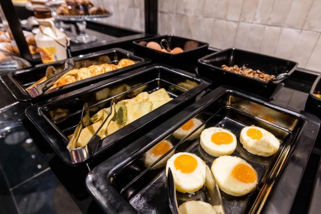 A buffet with various food items including eggs, pastries, and meat dishes.
