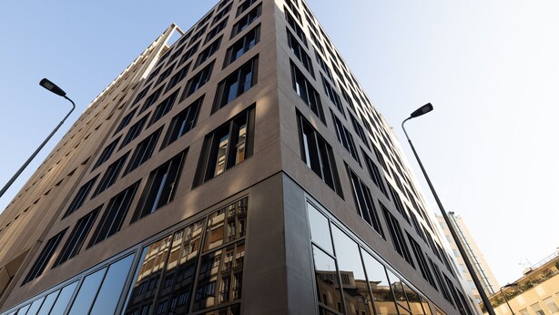 Een hoog, modern gebouw met een rastergevel en grote ramen.