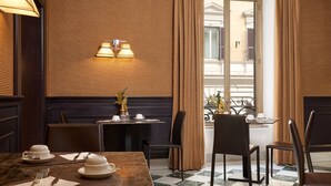 A dining area with a checkered floor, a table set with white plates and cups, and two wall-mounted lamps. - Mascagni Hotel (Rome)
